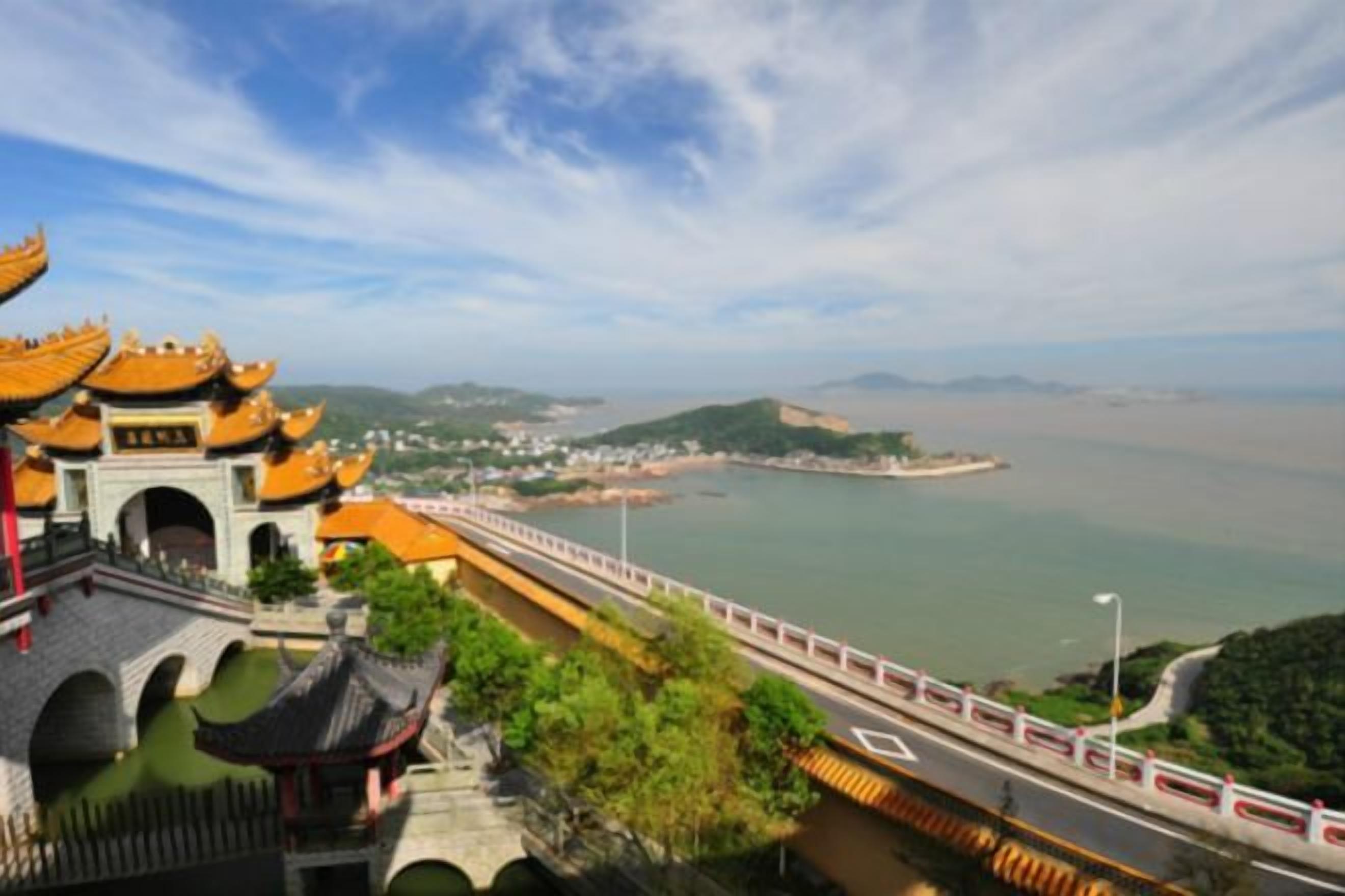 A traditional Chinese architectural structure with a view of a body of water and a distant coastline.