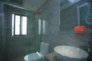 Ein modernes Badezimmer mit einer Duschkabine, einer Toilette und einem großen Waschbecken.