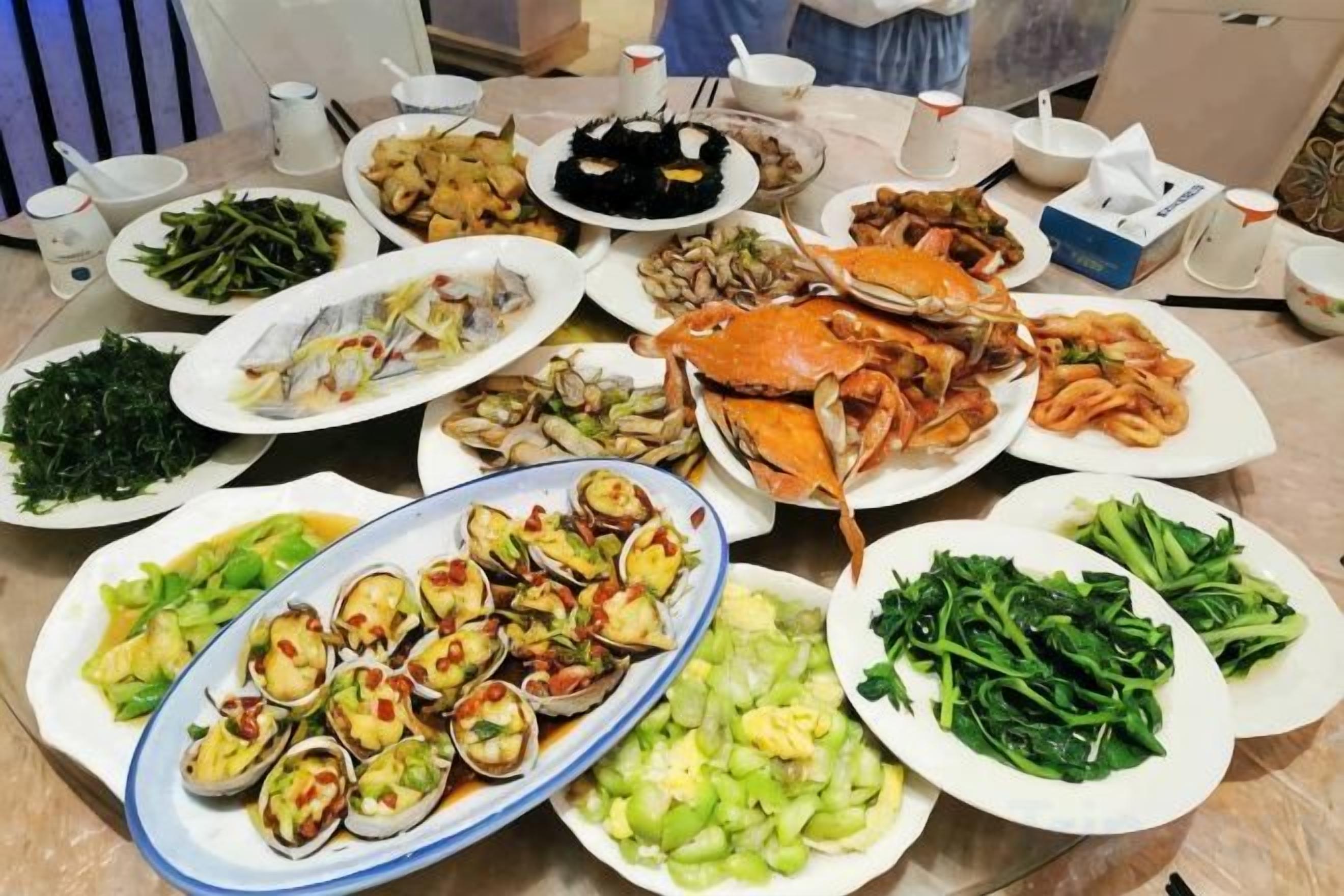 A table with various dishes including seafood, vegetables, and a large crab.