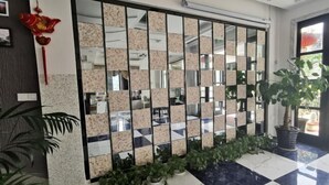Eine Lobby mit Schachbrettmuster-Boden, einem Spiegelteiler und Topfpflanzen.