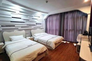 Habitación de hotel con dos camas, piso de madera, diseño moderno en la pared y un ventanal con cortinas.