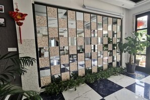 A lobby with a checkered floor, a mirrored wall, and potted plants.