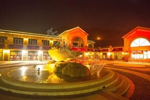 A public square with a central fountain, surrounding buildings with illuminated signs, and a circular walkway. - Shengsi Yihai House B & B (Shengsi)
