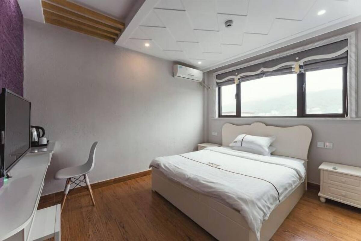 Ein Schlafzimmer mit Bett, Schreibtisch, Stuhl, Nachttisch und einem Fenster mit Blick.