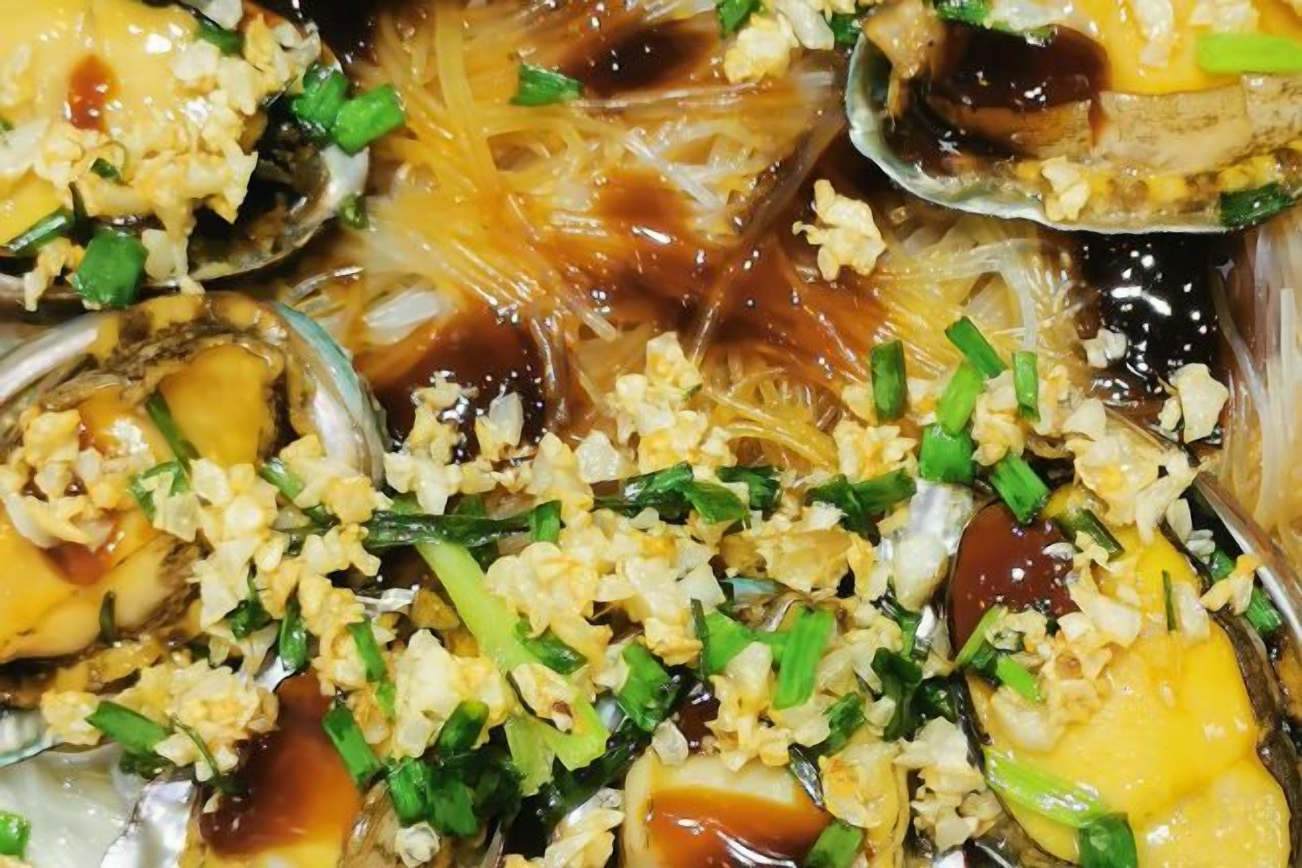 A close-up of a dish with noodles, eggs, and green onions.