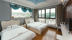 Ein Hotelzimmer mit zwei Betten, einem großen Fenster mit Vorhängen, einem Balkon und einem Fernseher.