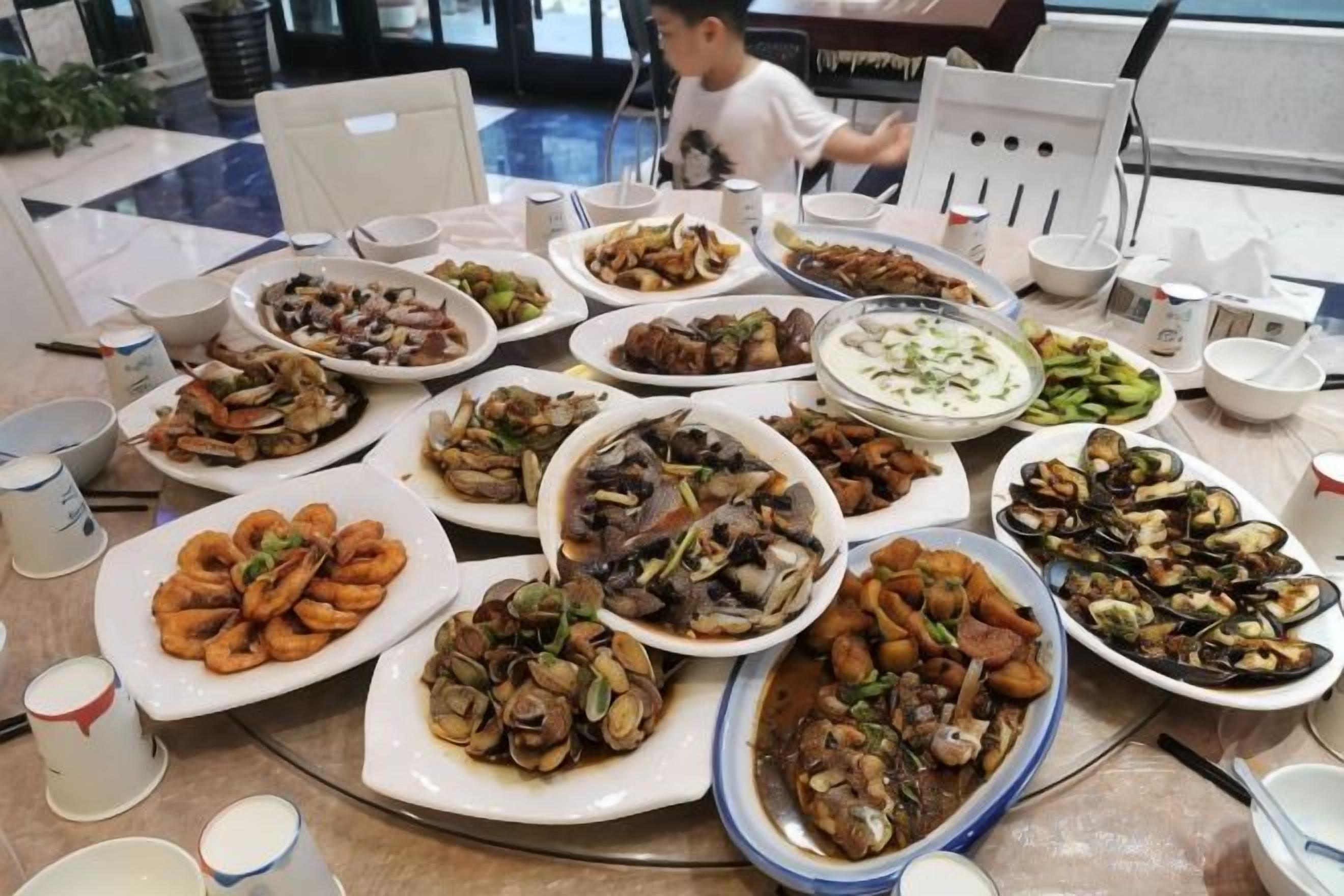 Una mesa de comedor con varios platos de mariscos, incluyendo mejillones y almejas, y una variedad de acompañamientos.