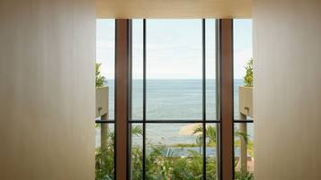A view from a balcony with large windows overlooking a body of water and a landscaped area.