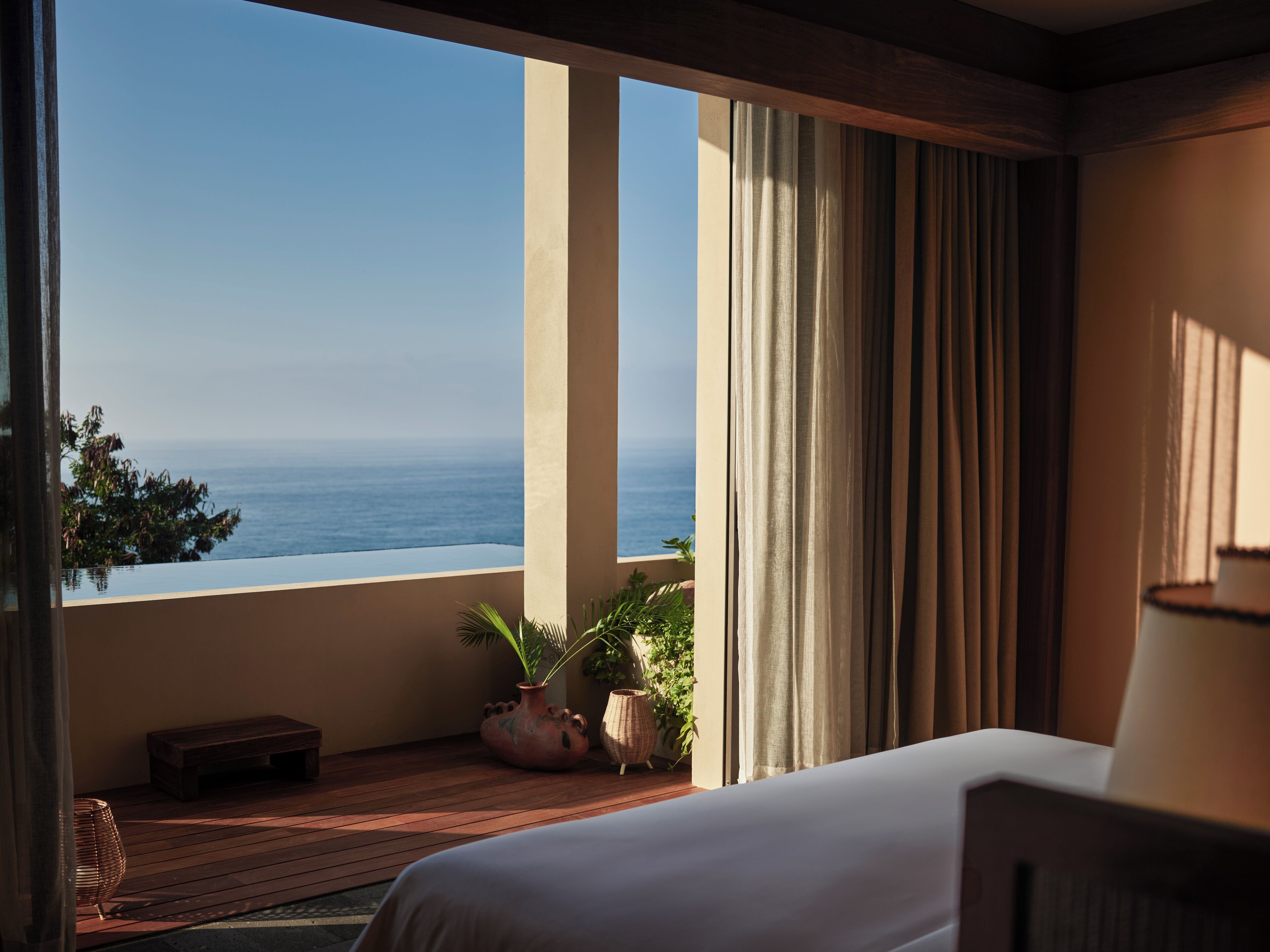 A bedroom with a large window overlooking a coastal view.