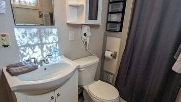 A bathroom with a sink, toilet, mirror, and shower curtain.