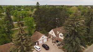 A residential area with a house featuring a garage, a driveway with two cars, and a patio area with outdoor furniture. - Studio Loft #9 at Riverside Point Resort (Park Rapids)