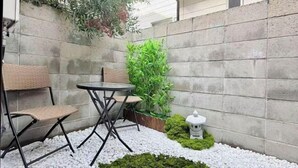 Un petit espace extérieur aménagé avec une table et des chaises, entouré de galets blancs et de verdure.