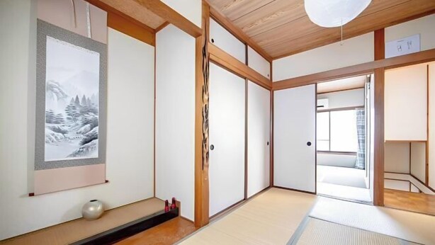 Une pièce de style japonais traditionnel, avec un sol recouvert de tatamis, des portes coulissantes et une œuvre d’art encadrée accrochée au mur.