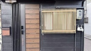 Une entrée fermée par un portail en métal, une clôture en bois et une caméra de surveillance.