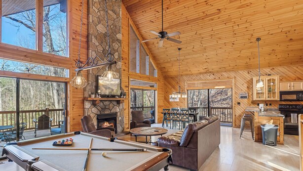 A spacious living area with a pool table, comfortable seating, a fireplace, and large windows offering views of the outdoors. - Mountain Views from Sofa and Huge Deck! (Gatlinburg)