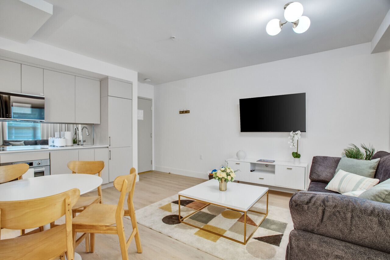 A modern living room with a white sofa, a coffee table, and a TV mounted on the wall.
