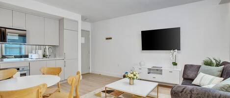A modern living room with a white sofa, a coffee table, and a TV mounted on the wall.