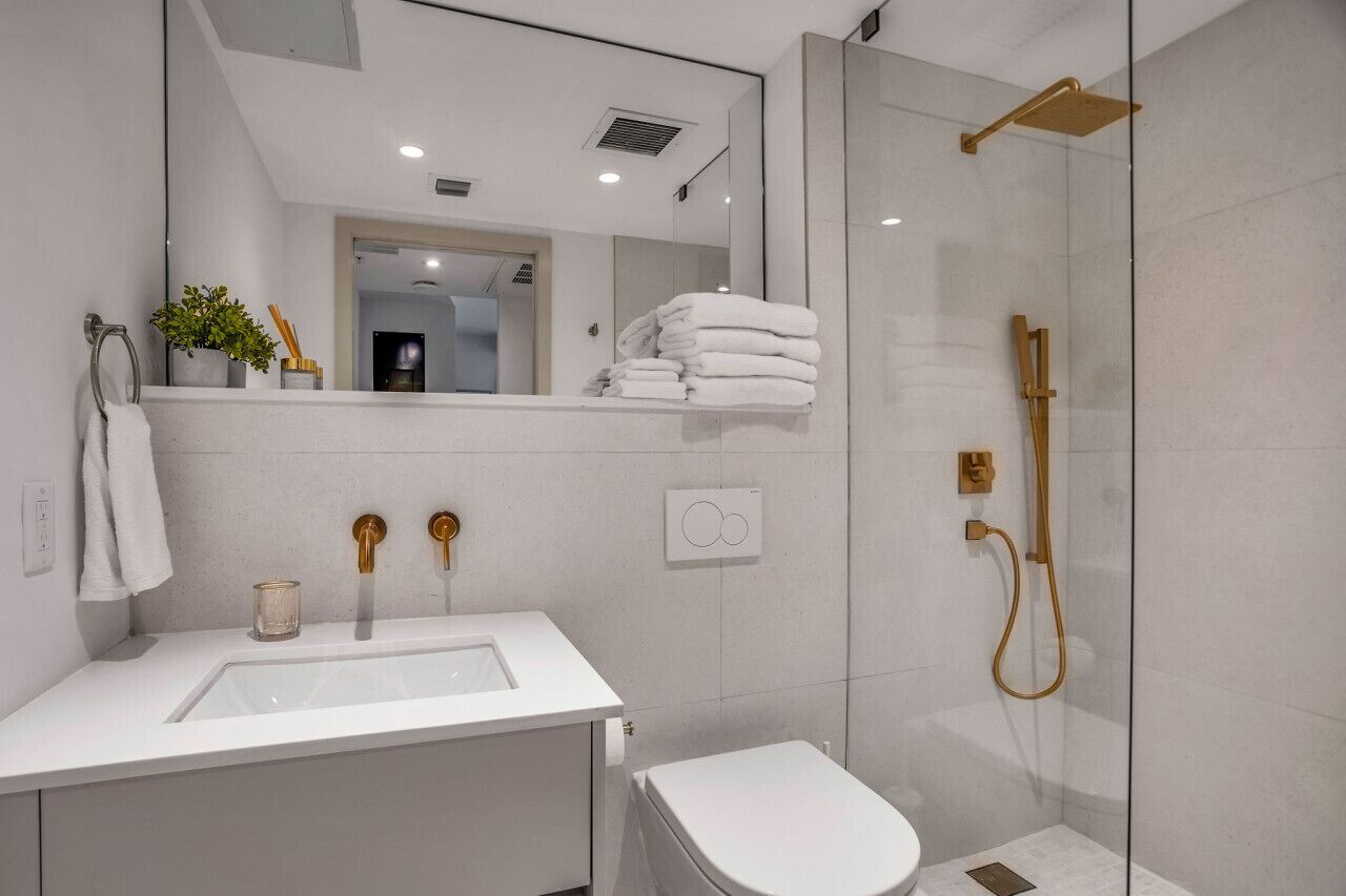 Une salle de bain moderne avec une douche à parois de verre, un lavabo blanc et des toilettes.