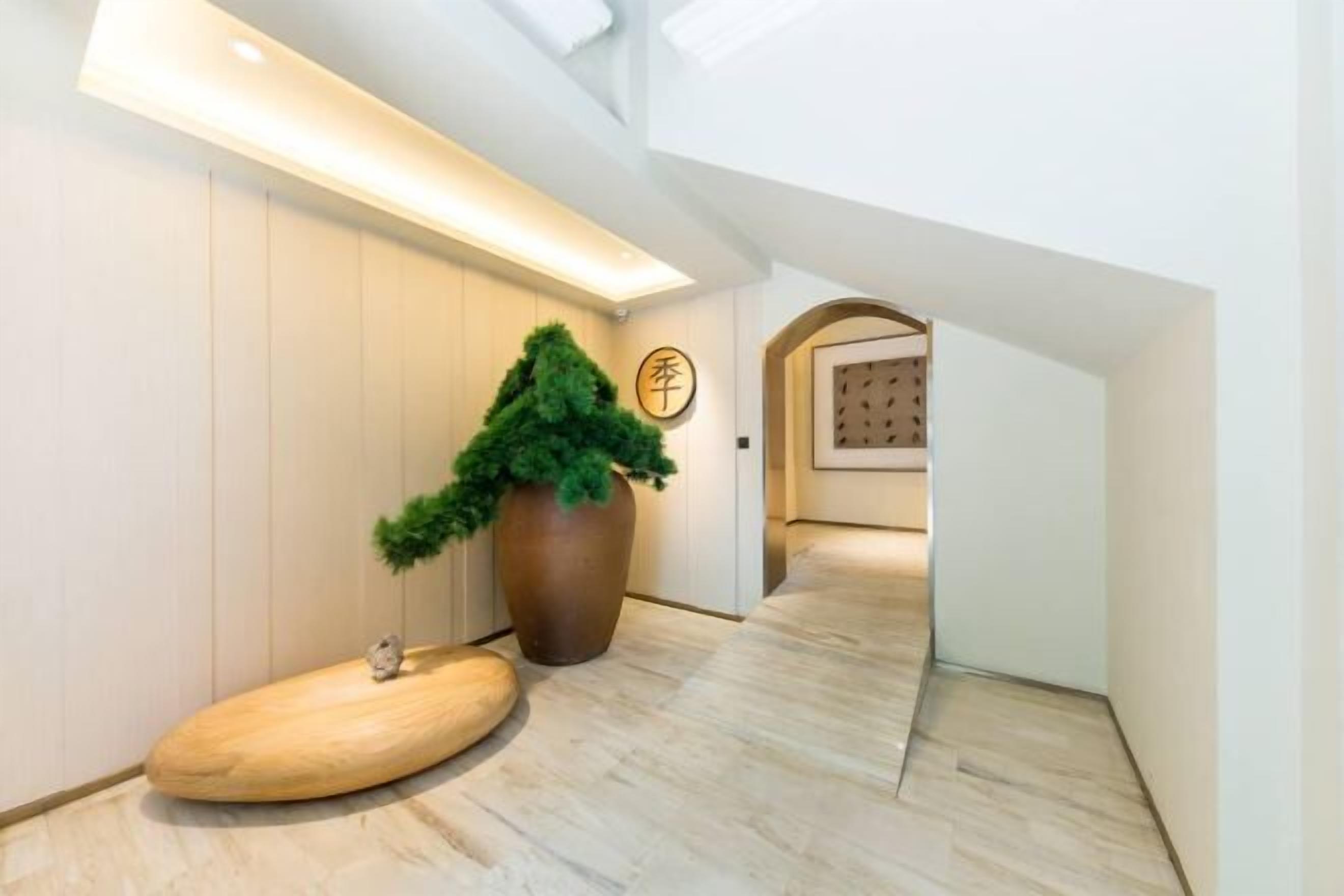 Ein modernes Interieur mit Holzboden, einer großen Pflanze im Topf und einem Empfangsbereich mit einem Schild.