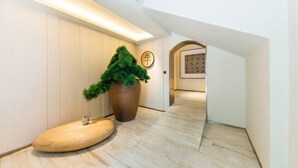 Un interior moderno con suelo de madera, una planta grande en maceta y una zona de recepción con un letrero.