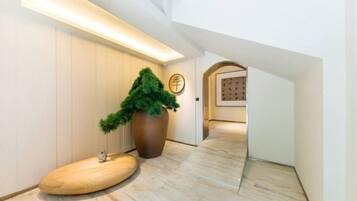 Ein modernes Interieur mit Holzboden, einer großen Pflanze im Topf und einem Empfangsbereich mit einem Schild.
