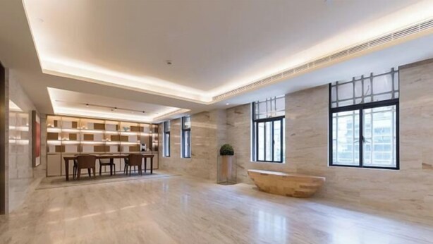 Un hall de hotel espacioso y moderno con suelo de mármol, mostrador de recepción, zona de estar y grandes ventanales que dejan entrar luz natural.