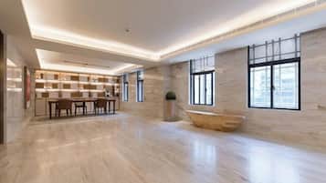 Eine geräumige, moderne Hotelhalle mit Marmorboden, einer Rezeption, einer Sitzecke und großen Fenstern, die für natürliches Licht sorgen.