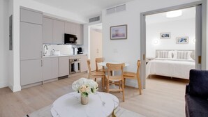 Un appartement moderne et bien éclairé, comprenant une cuisine, un coin repas et une chambre.