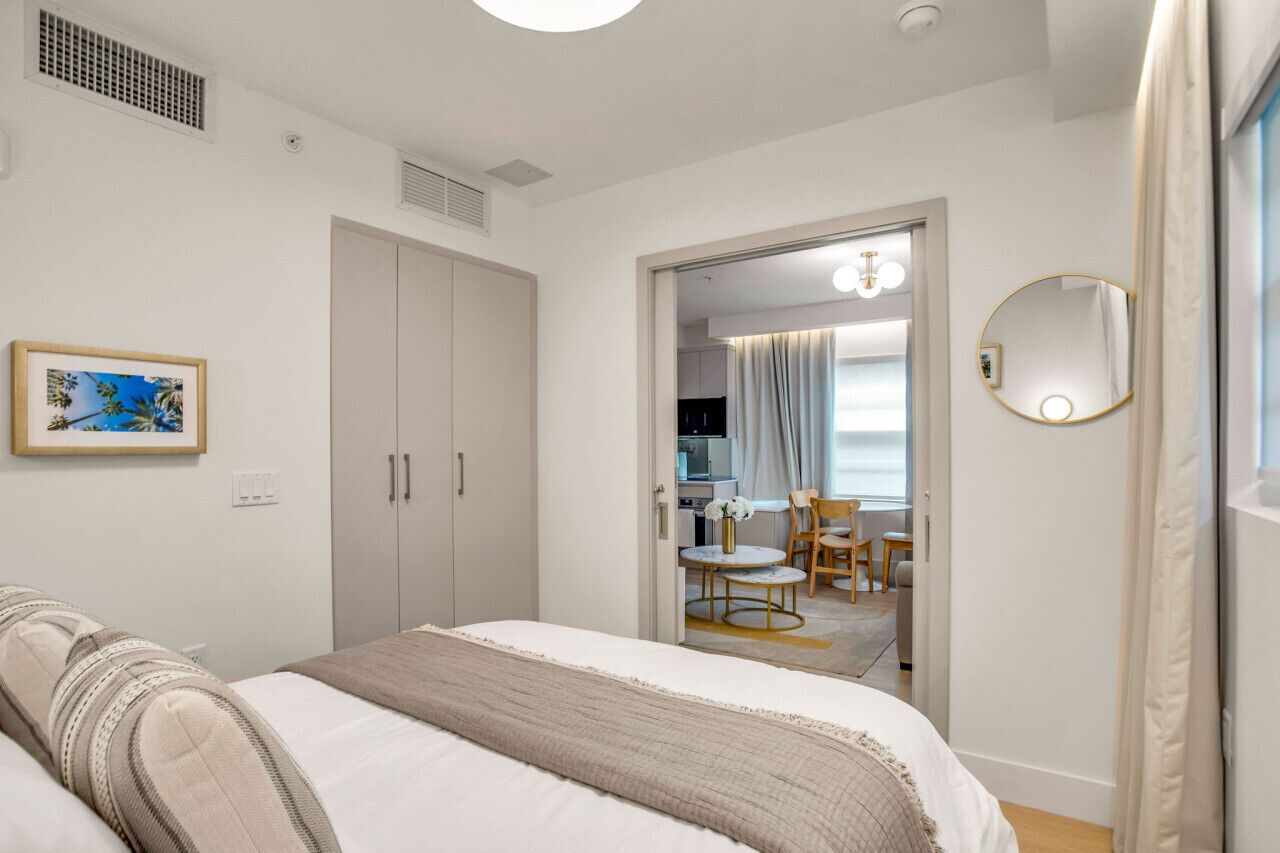 A bedroom with a bed, a wardrobe, a mirror, and a door leading to a bathroom.