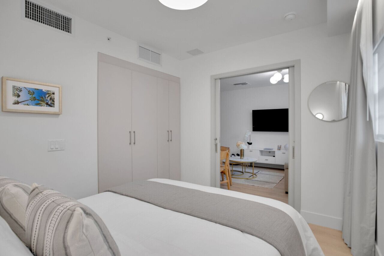 Ein Schlafzimmer mit Bett, Schrank, Spiegel und angrenzendem Badezimmer.