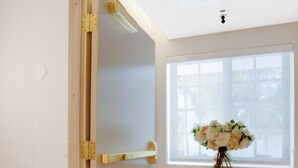 A room with a sliding door, a window with a view, and a console table with a vase of flowers. - Vonder Miami Beach - Unit 14 (Miami Beach)