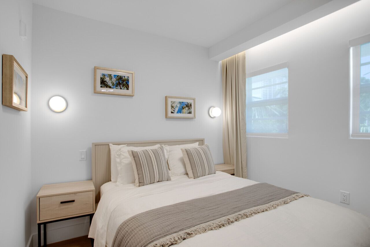 Een slaapkamer met een bed, nachtkastjes en wandlampen.