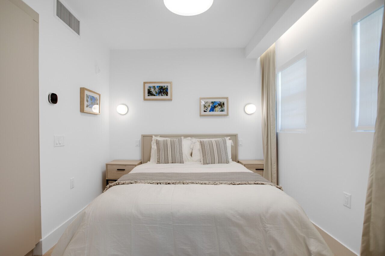 A bedroom with a bed, bedside tables, and framed pictures on the wall.
