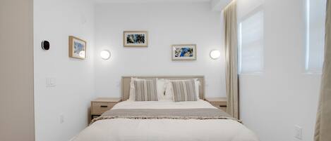A bedroom with a bed, bedside tables, and framed pictures on the wall.