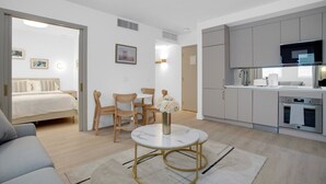 A modern hotel room with a bed, a dining area with a table and chairs, a kitchen with appliances, and a living area with a sofa. - Vonder Miami Beach - Unit 18 (Miami Beach)
