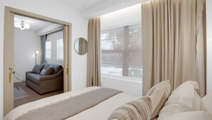 A modern hotel room with a large bed, a sofa, a mirror, and a view of the outdoors. - Vonder Miami Beach - Unit 18 (Miami Beach)