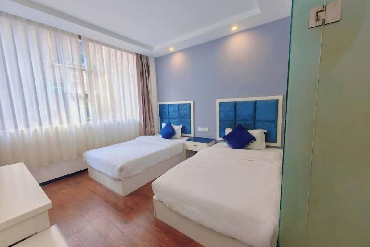 Habitación de hotel con dos camas individuales, un escritorio y una silla.