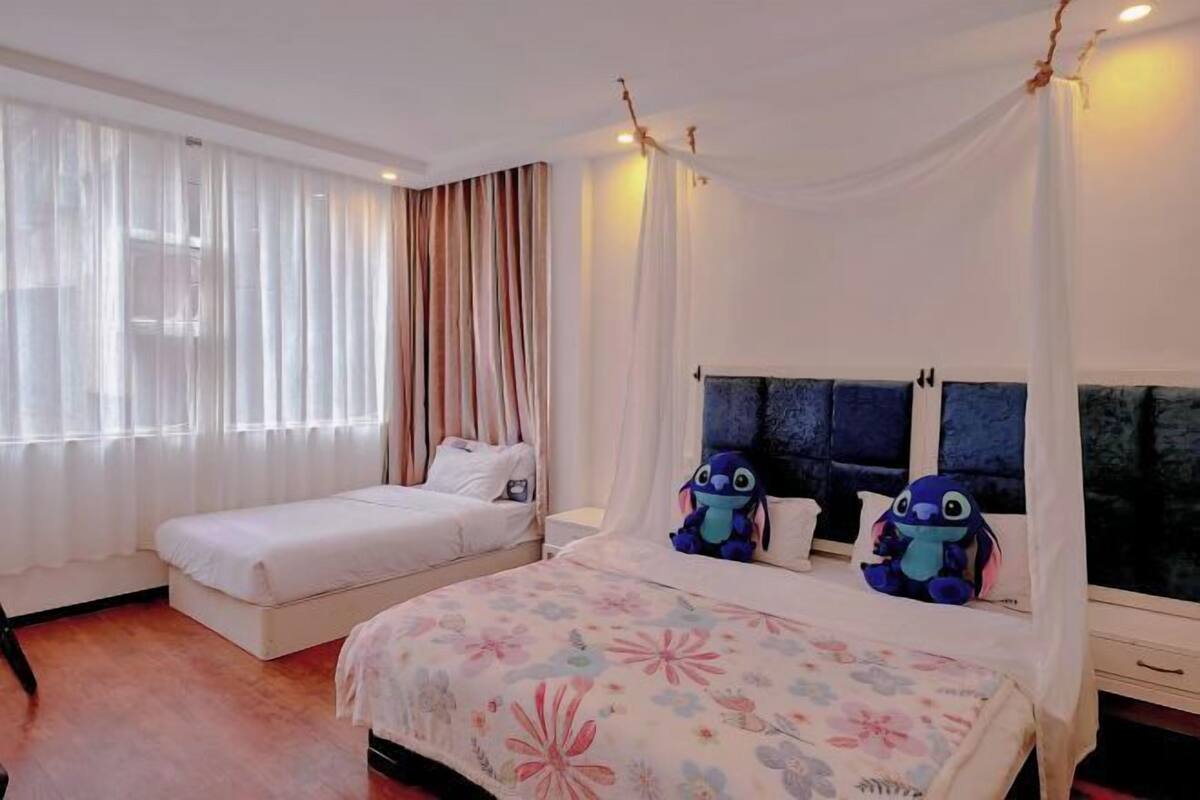 Habitación de hotel con dos camas, una con dosel y otra sin. Hay juguetes suaves en la cama con dosel.