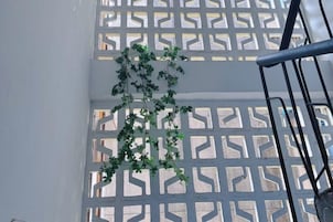 Escada com corrimão de metal e planta pendurada na parede.
