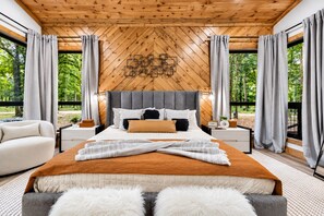 Une chambre moderne avec un grand lit, un plafond en bois et une vue sur la verdure environnante.