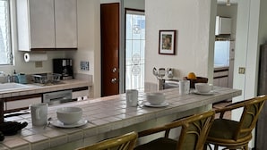 A modern kitchen with white cabinets, a large island with bar stools, and a view of the dining area.