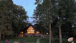 Een lodge met een houten gevel, een steiger en buitenmeubels aan het water.
