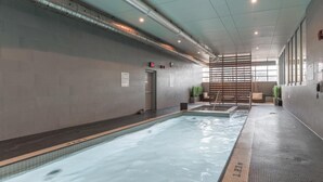 A swimming pool with clear water, tiled walls, and a tiled floor. There is a wooden ladder leading into the pool, and a door with an emergency exit sign. - GLOBALSTAY. High Floor in Downtown Toronto 1bd+den (Toronto/Canada)