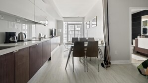 A modern kitchen with dark wood cabinets, a white countertop, and a dining area with a glass table and chairs. - GLOBALSTAY. High Floor in Downtown Toronto 1bd+den (Toronto/Canada)