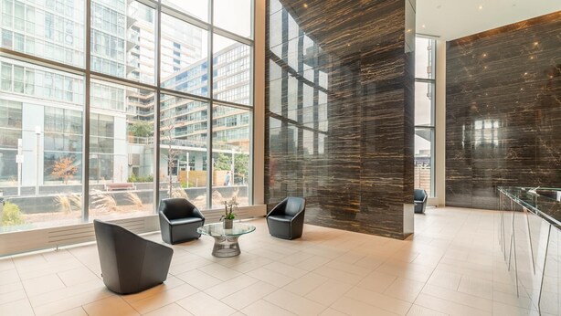 A modern lobby with large windows, black leather chairs, a glass coffee table, and a dark marble wall. - GLOBALSTAY. High Floor in Downtown Toronto 1bd+den (Toronto/Canada)