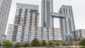 A modern high-rise building with multiple floors, large windows, and a prominent curved structure in the center. - GLOBALSTAY. High Floor in Downtown Toronto 1bd+den (Toronto/Canada)
