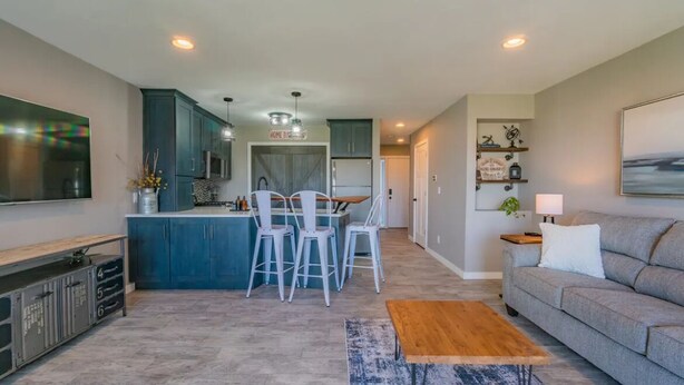 A modern living room with a grey sofa, a coffee table, and a TV mounted on the wall. - Charming 1-bedroom waterfront condo in fabulous Spring Lake. (Spring Lake)