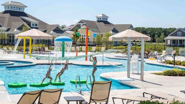 A swimming pool area with lounge chairs and umbrellas.