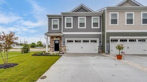 A two-story residential building with a garage and a well-maintained lawn.