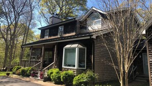 A two-story wooden house with a porch, a chimney, and a large window. - Cozy en-suite in beautiful East Hampton with AC, WiFi (East Hampton)